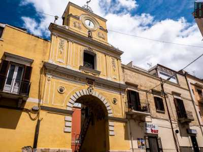 Proseguiamo lungo via Vittorio Veneto per un altro centinaio di metri. Sulla sinistra appare l'arco di accesso al centro storico del rione: una struttura color sabbia arricchita da cornicioni e decorazioni in pietra bianca